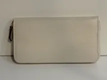 Billetera rectangular de cuero color beige con cierre perimetral y tirador de cuero. Cuenta con múltiples compartimentos internos para tarjetas, documentos y billetes, además de un bolsillo interno con cierre para monedas y forro textil en color rojo.