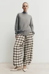 Pantalón bombacho de tiro alto con estampado de cuadros en tonos crudo y marrón. Presenta cintura elástica ajustable con cordón y bajos elásticos.