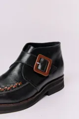 Botín de cuero negro con detalle de trama marrón en la puntera y hebilla cuadrada color carey.