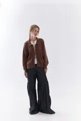 Cardigan de tejido de punto color marrón, con cuello solapa, cierre frontal de cremallera y diseño de trenzas. Cuenta con puños y dobladillo en rib elástico y un pequeño bordado en el pecho.