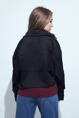Campera negra de estilo western con flecos en las mangas, corte cropped, bolsillos frontales y cierre con botones metálicos.