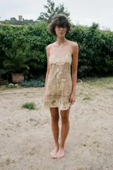 Vestido corto semitransparente de organza con escote en pico y tirantes finos. Presenta aplicaciones de bordados florales a contraste y detalles de cintas horizontales.