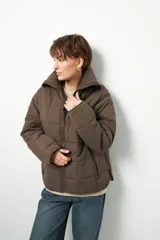 Campera acolchada de color marrón, con diseño capitoneado, cierre frontal completo y cuello alto de tejido acanalado.