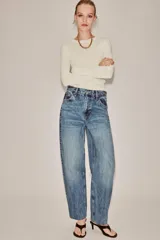 Jeans de tiro alto con corte tapered y largo al tobillo. Presenta cinco bolsillos, trabillas en la cintura, cierre frontal con cremallera y botón, y detalle de raya planchada en el delantero.