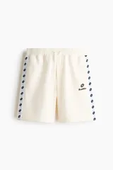 Short de felpa color beige de la marca Lotto, con cintura elástica con cordón de ajuste, bolsillos laterales y franjas laterales estampadas con el logo de la marca.