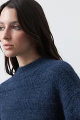 Sweater de punto color marrón chocolate, con cuello redondo, mangas largas abullonadas y puños ajustados. Presenta un diseño de textura acanalada horizontal y silueta relajada.