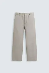 Pantalón de vestir color beige claro, de corte recto y holgado (regular fit), con cintura elástica y cierre frontal con botón y cremallera. Presenta bolsillos delanteros y bolsillos traseros de vivo.