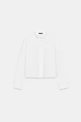 Camisa corta blanca de popelín con cuello solapa decorado con abalorios joya, manga larga y cierre frontal de botones.