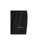 Pantalón de jogging Fear of God Essentials de corte acampanado, color negro, con cintura elástica con cordón ajustable y el texto "Essentials" estampado en la pierna izquierda.