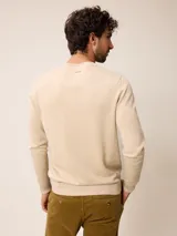 Sweater de punto con cuello redondo, manga larga y puños acanalados. Presenta un pequeño logo bordado en el pecho.
