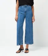 Pantalón de jean modelo wide leg cropped con cintura alta y sastre. Presenta costuras verticales frontales, bolsillos laterales y cierre delantero tradicional.