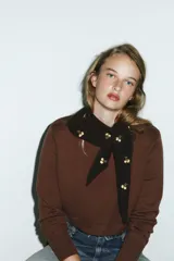 Bandana de tejido de punto en color marrón oscuro, con diseño triangular y detalle de pequeñas flores bordadas en color crema distribuidas por toda la prenda.