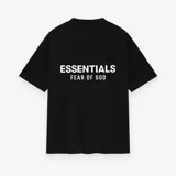 Camiseta negra de algodón con logo "Essentials Fear of God" estampado en blanco en la espalda. Corte oversize y cuello redondo.