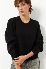 Sweater negro de punto con cuello redondo y mangas largas con puños elastizados.