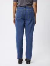 Jean de corte recto y tiro medio, con diseño clásico de cinco bolsillos. Presenta un lavado azul medio y terminación de ruedo desflecado.