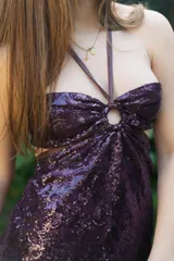 Vestido corto de satén color verde azulado (teal) con escote strapless y detalle de frunce central con argolla. Presenta tirantes finos que se atan al cuello y aberturas laterales en la cintura.