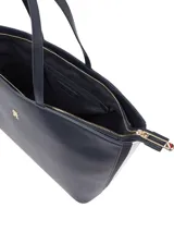 Cartera shopper azul marino de Tommy Hilfiger, confeccionada en poliuretano con doble asa superior y cierre de cremallera. Presenta el logotipo metálico de la marca en la parte delantera.