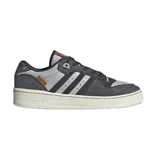 Championes adidas modelo Rivalry Low, con diseño de corte bajo. Presentan una combinación de paneles en cuero gris y denim oscuro con bordes deshilachados. Incluyen las icónicas tres tiras laterales en negro, suela de goma color crema y detalles en cuero marrón en la lengüeta y el lateral.
