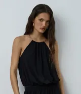 Body de microfibra color negro con diseño de frente única y detalle de adorno metálico tipo collar en el cuello. Presenta una caída fluida y espalda descubierta, ideal para un look sofisticado.