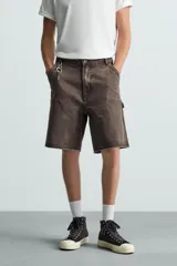 Bermuda relaxed fit confeccionada en tejido de algodón con efecto lavado. Presenta un diseño de cinco bolsillos, bolsillo multifunción en la pernera y tira lateral de estilo carpintero. Cuenta con cierre frontal con cremallera y botón.