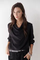 Blusa negra de diseño fluido con cuello buche y mangas largas con puño. Confeccionada en una mezcla de rayón, chinlon, lyocell y lino.