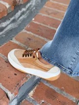 Zapatillas deportivas de cuero color camel con cordones marrones y suela blanca.