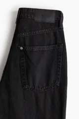Jean de tiro extraalto con diseño de cinco bolsillos, confeccionado en denim de algodón rígido. Presenta un corte holgado en cadera y muslos con pierna amplia de estilo recto.