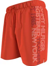 Short de baño Tommy Hilfiger color naranja, con cintura elástica ajustable mediante cordón. Presenta un diseño liso con el logo de la marca estampado verticalmente en el lateral izquierdo.