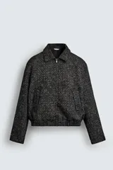 Cazadora de corte relajado confeccionada en tejido jacquard con textura. Presenta cuello solapa, cierre frontal con cremallera, bolsillos de vivo en la cadera y bajo con acabado elástico.
