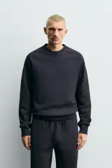 Sudadera de corte relajado confeccionada en algodón compacto con interior de rizo. Presenta cuello redondo, mangas largas tipo raglán y terminaciones en rib.
