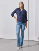 Blusa blanca de gasa marca Zac & Rachel, con cuello a la base, escote en V, abertura central con botones, bolsillo aplicado en el pecho y mangas largas regulables con presilla y botón. Tiene terminación opcional de nudo en el ruedo.