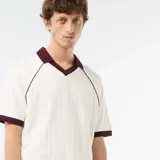 Remera de tejido de punto color blanco con cuello en V y cuello polo en contraste bordó, al igual que los ribetes en los puños y las costuras de las mangas raglán.