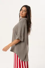 Camisa verde de silueta oversize con cuello camisero y manga 3/4. Tiene bordados de coral y caracol en el frente y botones a tono.