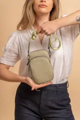 Bandolera compacta color rojo con textura de cuero, correa regulable y desmontable con diseño de rayas rojas y blancas. Cuenta con bolsillos frontales y cierre, interior forrado en tela.