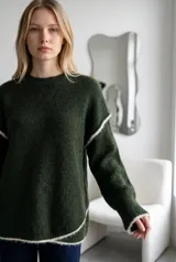 Sweater de punto gris con textura suave, diseño oversize, cuello redondo y detalles de costuras expuestas en color blanco en mangas y ruedo.