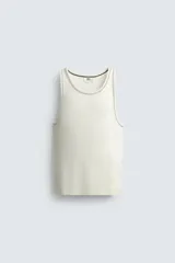 Camiseta tipo tank top de corte slim fit, color blanco hueso, con cuello redondo amplio y sisas terminadas con pespunte contrastante en color oscuro.
