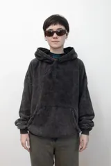 Canguro con capucha de calce holgado, confeccionado en tejido con efecto lavado ácido en color gris oscuro. Presenta un bordado tonal en el centro del pecho y un bolsillo frontal tipo canguro.