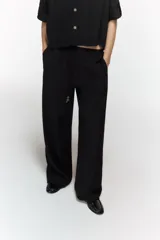 Pantalón fluido de tiro alto color verde militar, con cintura elástica ajustable con cordones y detalles de cuentas de madera. Tiene bolsillos delanteros y pierna recta.