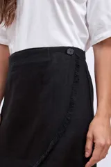 Minifalda color beige de corte evasé con diseño cruzado y detalle de flecos en el ruedo.