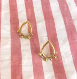 Par de aros dorados con forma de gota y detalle de bolitas.