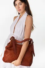 Cartera tipo hobo color suela, confeccionada en cuero con diseño trenzado y correa ajustable con hebilla metálica dorada.
