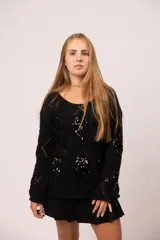 Buzo negro de tejido de punto con diseño calado de rombos y apliques de lentejuelas negras en el frente y las mangas.