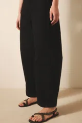 Jean de tiro medio-alto, color negro, de calce holgado con piernas anchas que se estrechan hacia el tobillo. Presenta pinzas en las rodillas que acentúan su forma "balloon" y un recorte lateral. Confeccionado en denim rígido con lavado suavizado, cierre y botón.