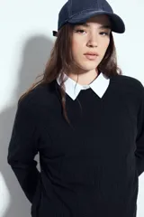 Sweater de punto color negro, con cuello redondo y diseño texturizado con ondas en relieve. Presenta mangas largas y un calce cómodo y holgado.