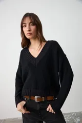 Sweater de punto texturizado color negro, con cuello en V acanalado, mangas largas y corte holgado con terminaciones en puños y ruedo acanalados.