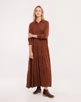 Vestido largo color marrón con cuello camisero, manga larga con puños elásticos y falda escalonada con volados.