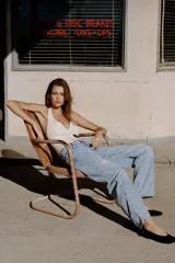 Jeans de tiro medio con corte baggy, pernera holgada que se estrecha hacia el tobillo. Presenta diseño de cinco bolsillos, cierre frontal con cremallera y botón, y detalles de roturas con aplicaciones de encaje en el frente.