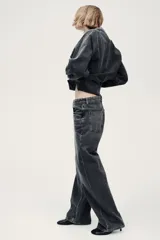 Jean de corte baggy, estilo holgado con piernas rectas, confeccionado en denim de algodón color gris oscuro con efecto lavado. Cuenta con tiro estándar, trabillas para cinto, cierre frontal con botón y cinco bolsillos clásicos.