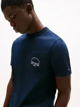 Remera de algodón de corte regular, color azul marino, con cuello redondo y bolsillo de parche en el pecho que incluye un logo arqueado de la marca. Presenta un logo bordado en la manga.