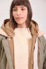 Campera acolchada reversible con capucha, diseño de matelassé, cierre frontal y puños elásticos. Presenta un lado en color verde oliva y otro en color beige.